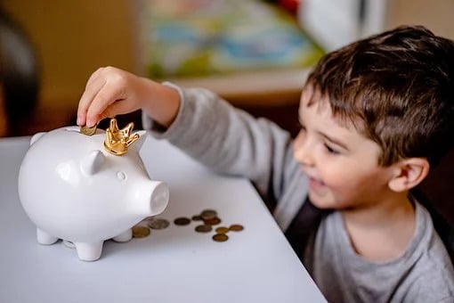 Young Child Saving Coins in Piggy Bank